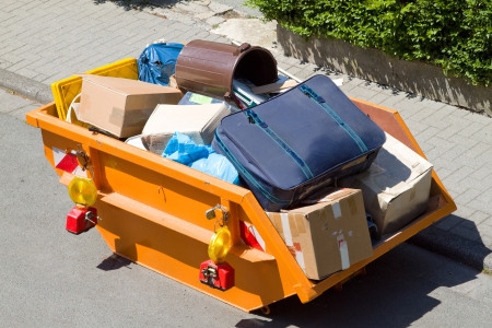 Ein großer Sperrmüllcontainer, gefüllt mit verschiedenen Kartons, einem großen Koffer und Müllsäcken.